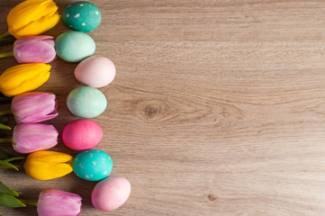 Obraz premium Easter composition of the tulips colored eggs cooked for the holiday on the wooden background