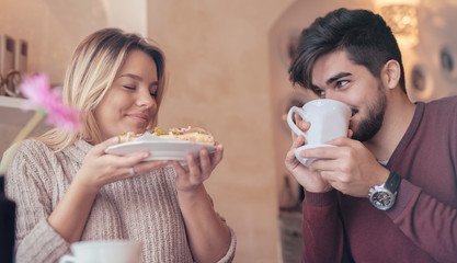 Beautiful young couple sitting in a cafe, having breakfast. Love, dating, relationships, food, lifestyle concept