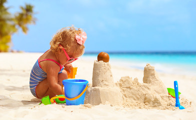 cute little girl playing with sand on beach