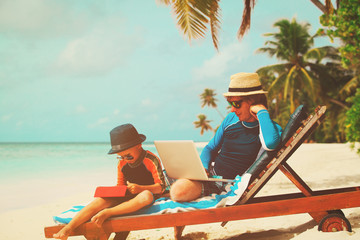 family with laptop and touch pad on beach