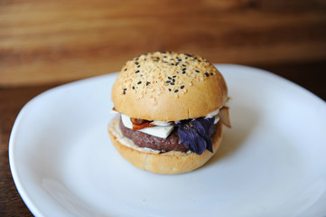Burger on a white plate. Wooden background