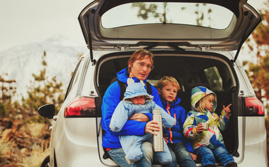family travel by car- happy father with three kids in mountains
