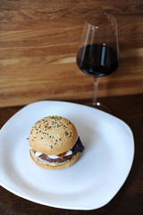 Burger and a glass of red wine on a wooden background. Free space for design