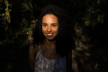 portrait outdoors of a beautiful young afro american woman smiling at sunset. Black background. Lifestyle