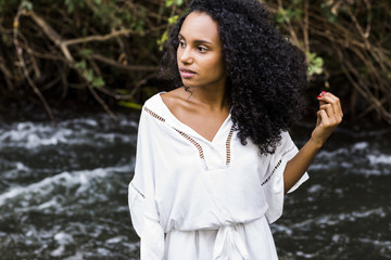 portrait outdoors of a beautiful young afro american woman at sunset. Green background. Lifestyle