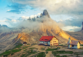 Scenic view of mountain hut and chapel at sunset in Dolomites, Italy - obrazy, fototapety, plakaty