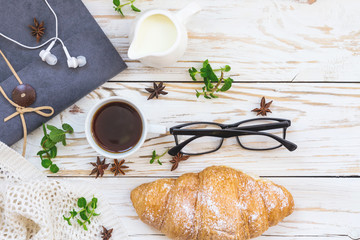 Croissant, coffee, headphones and notebook. Workplace and Leisure concept