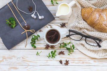 Croissant, coffee, headphones and notebook. Workplace and Leisure concept