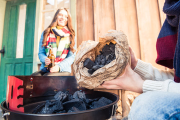 Close-up view of man filling grill with charcoal near smiling woman