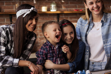 Two young women and two kids have fun in the kitchen