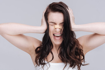 Fototapeta premium Hysteric tired young girl covering her ears