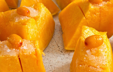 Raw sliced pumpkin with sea-buckthorn and sugar on top ready to bake.Close up view.