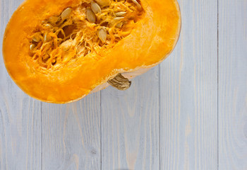 Pumpkin cut open with seeds on blue wooden background.