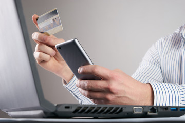 Online payment,Man's hands holding a credit card and using smart phone &  laptop for online shopping.