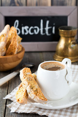 Homemade biscotti with nuts and a cup of coffee on the old wooden table background. Selective focus.