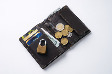 Open brown leather wallet with dollar cash, coins, debit credit cards inside and locked pad lock.Business safety and finance protection concept