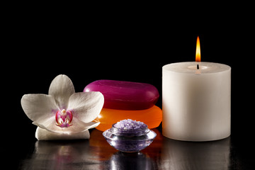 Fototapeta na wymiar White orchid flower, candle, soap and sea salt for spa procedures on black background