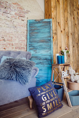 Large violet pillow with lettering 'Play, give, smile' lies before couch on the floor