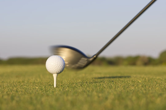 Closeup image of a golf club about to hit a golf ball.