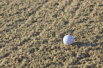Lonely golf ball in sand bunker.