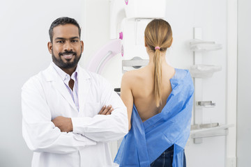 Doctor Standing Arms Crossed While Woman Undergoing Mammogram X-