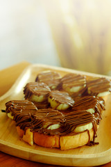 Toast with banana and hazelnut spread on light wooden tray. have some space for write wording