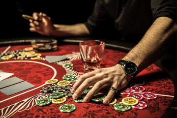 Close-up partial view of man holding poker chips while sitting at table in casino