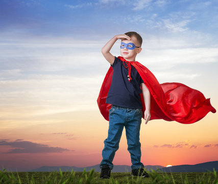 A boy in a Superman costume stands