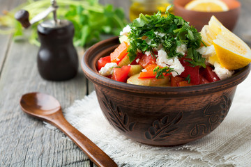 Fresh Salad Shopska of baked peppers, tomato, onion, cucumber, parsley, dill and feta cheese in a ceramic bowl. Traditional Serbian food. Selective focus.