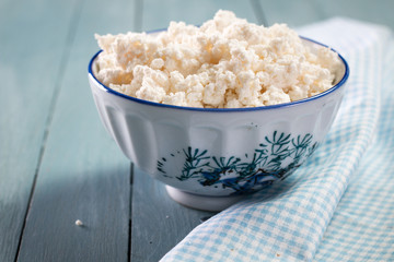 Homemade cottage cheese in a bowl on old wooden table.