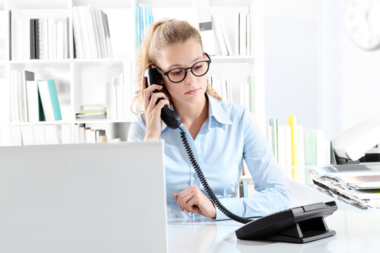 woman talking on phone in office at desk in front of computer