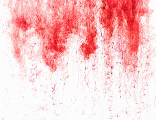 Color ink drop in water, photographed in motion, swirling. Red icloud of paint on white background.