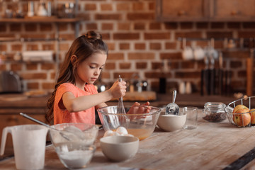 'focused girl mixing ingredients for dough for cake
