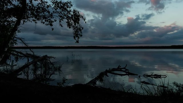 Sunset clouds over the forest lake. Time-lapse