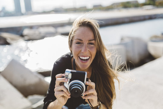 Portrait of happy young woman with old-fashioned camera at the seafront
