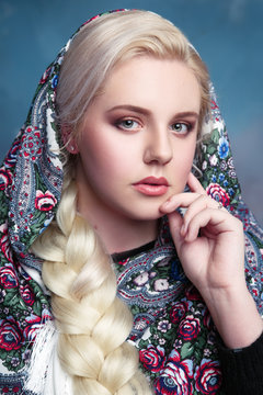 Portrait of a beautiful statuesque girl in the painted scarf on cloudy background.