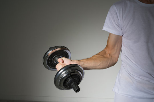 Young Man in a white shirt doing biceps exercises.
