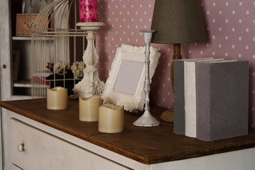 Chest of drawers with books, lamp, photo frame and candles