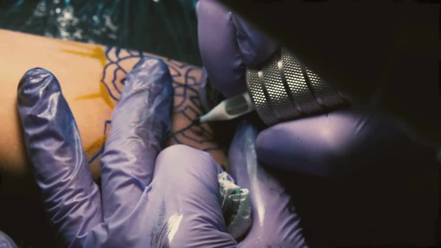 Tattoo master in gloves does tattoo close-up