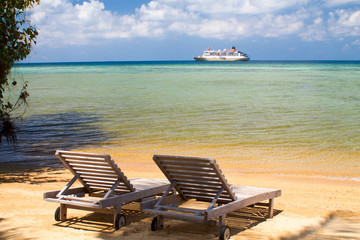 beach sunbeds in front of the sea with cruise ship