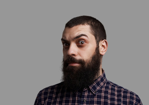 Long beard and big mustache face with raised eyebrow. Brutal and serious man shot isolated on neutral grey background. Person with anxious emotion.
