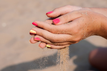 Girl sifting sand through her fingers. Hands close-up