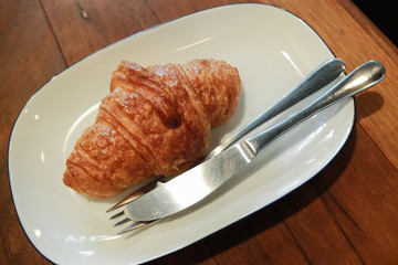 Plain croissants in white plate on wood table