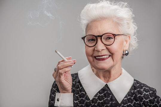 Emotional senior lady smoking with joy