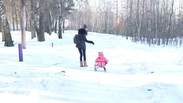 mom rolls her baby on a sled