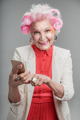 Happy modern senior female holding cellphone in hand