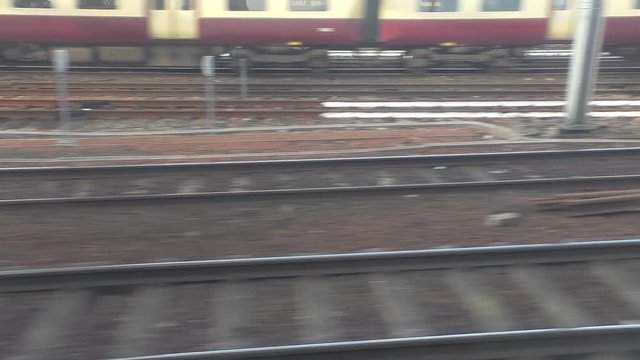 Commuter train car window view of railway tracks.Approaching Scotland's city Glasgow, after camera lift bridges and buildings on riverside are in a view