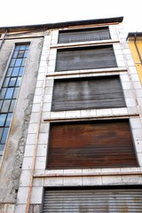 Fototapeta na wymiar Old and damaged facade of uninhabited building.