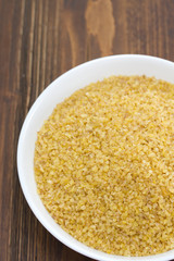 bulgur on white dish on brown background