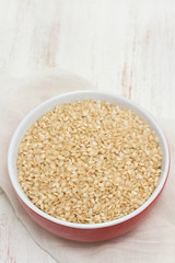 raw rice in red bowl on wooden background